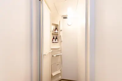 a small bathroom with a white door and shelves at The Felice Uguisudani - Vacation STAY 96241 in Tokyo