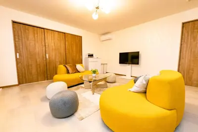 a living room with two yellow chairs and a tv at The Felice Uguisudani - Vacation STAY 96241 in Tokyo
