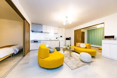 a living room with yellow chairs and a bed at The Felice Uguisudani - Vacation STAY 96242 in Tokyo