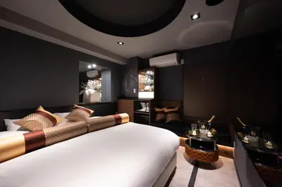 a bedroom with a large white bed and a living room at HOTEL VARKIN Ikebukuro Nishiguchi in Tokyo