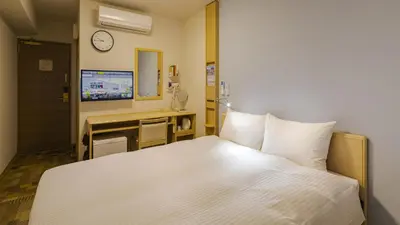 a bedroom with a bed and a desk with a clock at Toyoko Inn Tokyo Ikebukuro Kita guchi No 2 in Tokyo