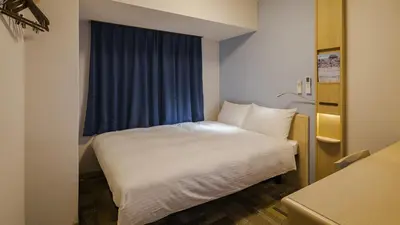 a bedroom with a white bed and a blue window at Toyoko Inn Tokyo Ikebukuro Kita guchi No 2 in Tokyo