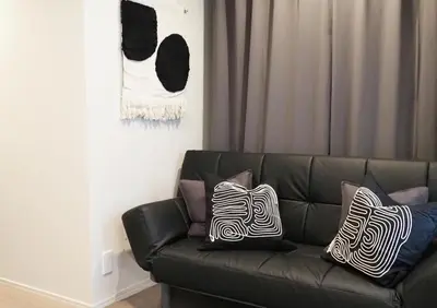 a black leather couch with two pillows on it at LANG HOTEL Kameido#Near Akihabara#\u30c1\u30a7\u30c3\u30af\u30a2\u30a6\u30c8\u306e\u307f\u6e05\u6383\u3042\u308a in Tokyo