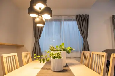 a dining room table with a vase of flowers on it at Y's HOTEL KAMEARI in Tokyo