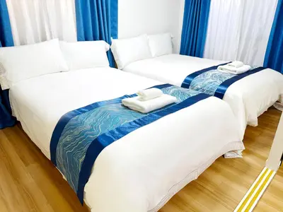 two twin beds in a room with blue curtains at Rosenheim Tokyo Shinjuku in Tokyo
