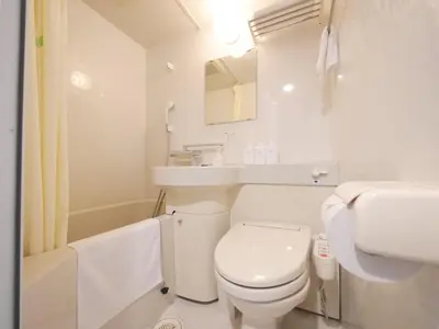 a white bathroom with a toilet and a sink at Hotel Comfybed Ginza in Tokyo