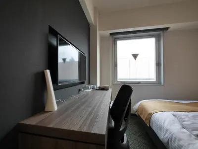 a bedroom with a desk and a bed and a window at Hotel Comfybed Ginza in Tokyo