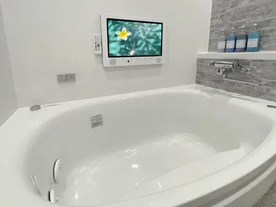 a white bath tub in a bathroom with a tv at Hotel BaliBali ANNEX \u4e94\u53cd\u7530 in Tokyo