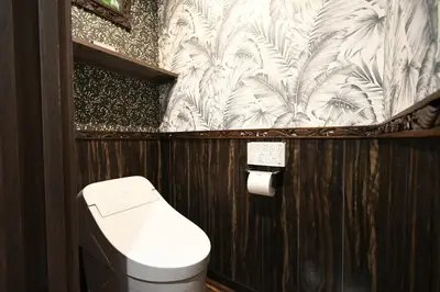 a bathroom with a toilet and a wallpaper with palm trees at Hotel BaliBali ANNEX \u4e94\u53cd\u7530 in Tokyo
