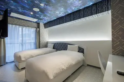 two beds in a room with a star ceiling at Hotaku HOTEL Akihabara in Tokyo
