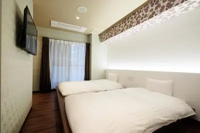two beds in a room with a tv and a window at Hotaku HOTEL Akihabara in Tokyo