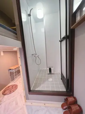a bathroom with a shower with a glass door at \u8aa0\u5bb6\u3000MAKOTO HOSTEL in Tokyo