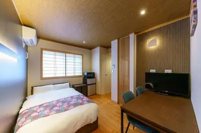 a bedroom with a bed and a desk and a television at YADOYA Suzume in Tokyo