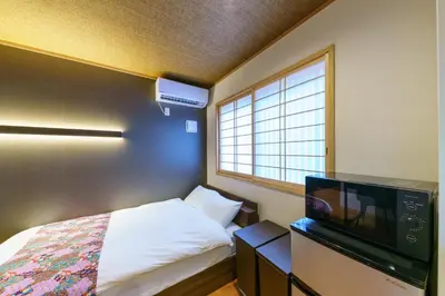 a small bedroom with a bed and a tv at YADOYA Suzume in Tokyo
