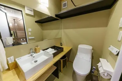 a bathroom with a sink and a toilet and a mirror at YADOYA Suzume in Tokyo