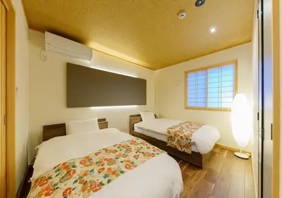 a bedroom with two beds and a flat screen tv at YADOYA Suzume in Tokyo