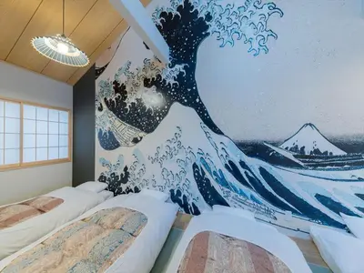 a bedroom with two beds and a mural of a wave at YADOYA Negishi in Tokyo