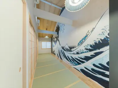 a hallway with a painting of waves on the wall at YADOYA Negishi in Tokyo