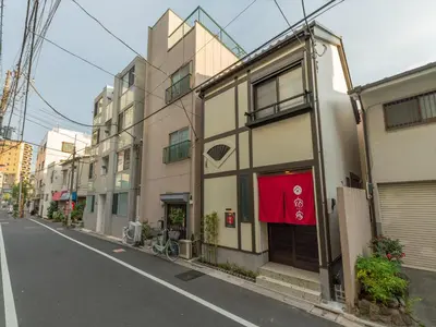 a building with a red door on a street at YADOYA Negishi in Tokyo