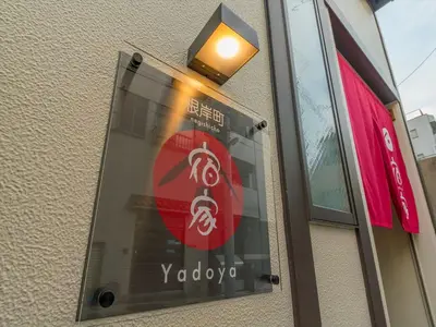 a sign on the side of a building with a light on it at YADOYA Negishi in Tokyo