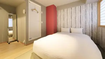 a bedroom with a white bed and a red wall at Tamayura Hotel Asakusa in Tokyo