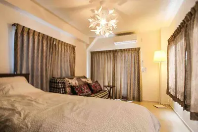 a bedroom with a bed and a chair and a chandelier at Guest house \u83ef\u97f3 in Tokyo
