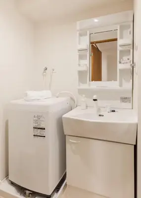 a white bathroom with a sink and a mirror at Dash Living Shinjuku in Tokyo
