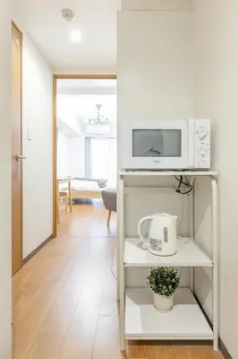 a kitchen with a microwave on a white shelf at Dash Living Shinjuku in Tokyo