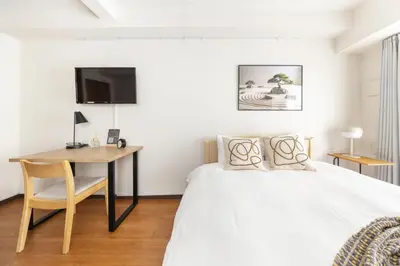 a bedroom with a bed and a desk and a tv at Dash Living Shinjuku in Tokyo