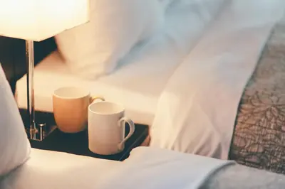 two cups on a table next to a bed at Kuretake Inn Premium Hamamatsucho in Tokyo