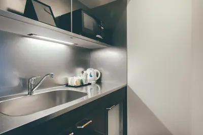a kitchen with a stainless steel sink and black cabinets at Kuretake Inn Premium Hamamatsucho in Tokyo