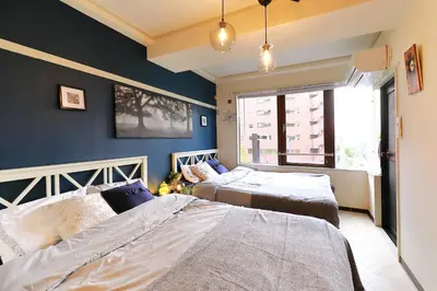 two beds in a room with blue walls at \u56db\u8c37\u677e\u672c\u9928\u30d3\u30eb in Tokyo