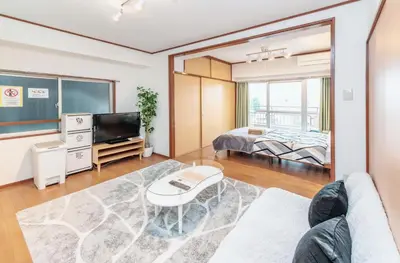 a living room with a couch and a tv and a bed at \u56db\u8c37\u677e\u672c\u9928\u30d3\u30eb in Tokyo