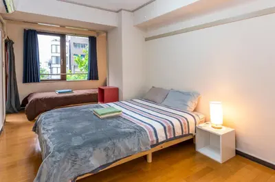 a small bedroom with a bed and a window at \u56db\u8c37\u677e\u672c\u9928\u30d3\u30eb in Tokyo