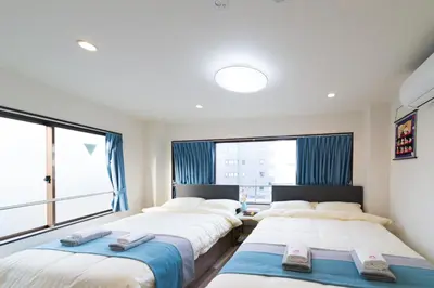 three beds in a room with a window at High Five Guest House in Tokyo