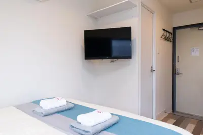 a room with a bed with two towels and a flat screen tv at High Five Guest House in Tokyo