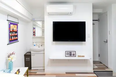 a living room with a tv on a white wall at High Five Guest House in Tokyo
