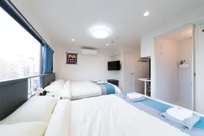 a hotel room with two beds and a window at High Five Guest House in Tokyo