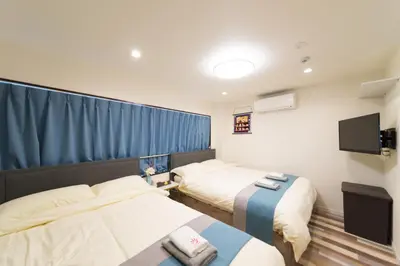 a hotel room with two beds and a flat screen tv at High Five Guest House in Tokyo