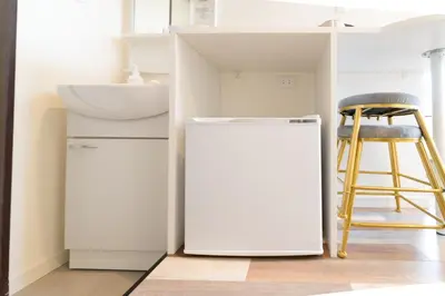 a kitchen with a white refrigerator and a stool at High Five Guest House in Tokyo