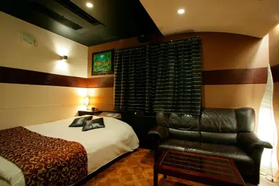 a bedroom with a bed and a leather chair at HOTEL CHECK INN BALI adult only in Tokyo