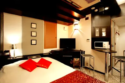 a bedroom with a large white bed with red pillows at HOTEL CHECK INN BALI adult only in Tokyo