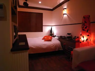 a bedroom with a bed and a desk with a television at HOTEL CHECK INN BALI adult only in Tokyo