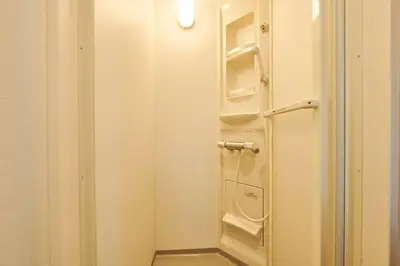 a small white bathroom with a shower with shelves at \u4e0a\u843d\u5408\u30cf\u30a6\u30b9 KAMIOCHIAI HOUSE in Tokyo