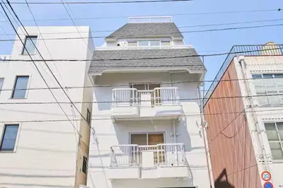 a white building with a balcony on the side of it at \u6c5f\u6238\u5ddd\u6a4b\u30ec\u30b8\u30c7\u30f3\u30b9 EDOGAWABASHI RESIDENCE in Tokyo