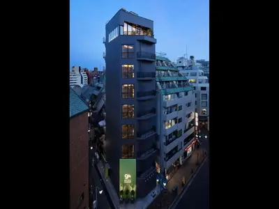a tall building with lights on in a city at 9h nine hours woman Shinjuku in Tokyo