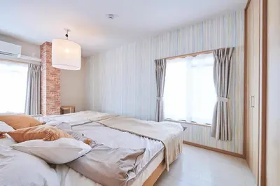 a bedroom with two beds and two windows at \u738b\u5b50\u795e\u8c37\u30cf\u30a6\u30b9 OJIKAMIYA HOUSE in Tokyo