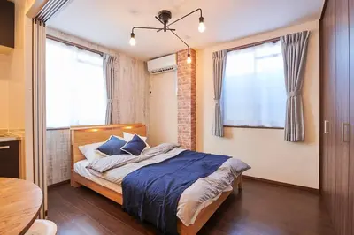 a bedroom with a bed with blue sheets and two windows at \u738b\u5b50\u795e\u8c37\u30cf\u30a6\u30b9 OJIKAMIYA HOUSE in Tokyo