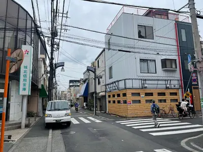 a white van is driving down a city street at \u738b\u5b50\u795e\u8c37\u30cf\u30a6\u30b9 OJIKAMIYA HOUSE in Tokyo