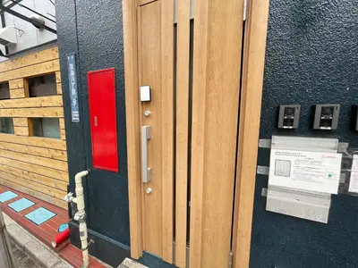 a wooden door with a red box on a building at \u738b\u5b50\u795e\u8c37\u30cf\u30a6\u30b9 OJIKAMIYA HOUSE in Tokyo